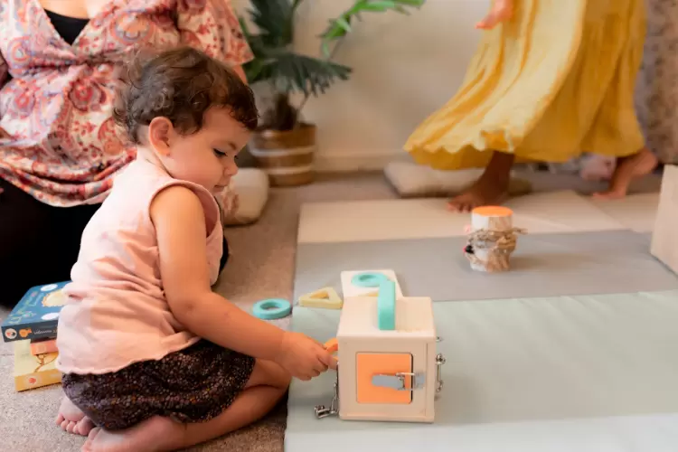 Photo d'un bébé qui joue avec un cube d'activité Montessori
