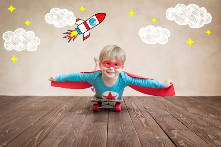 Photo d'un petit garçon déguisé en superhéros allongé sur son skateboard
